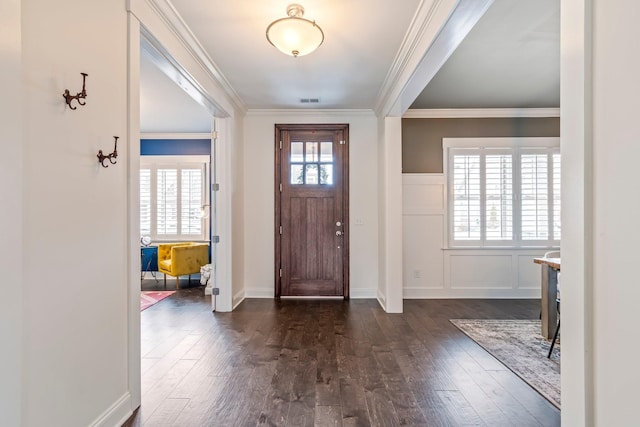 foyer entrance featuring crown molding, dark wood-type flooring, a decorative wall, and a healthy amount of sunlight