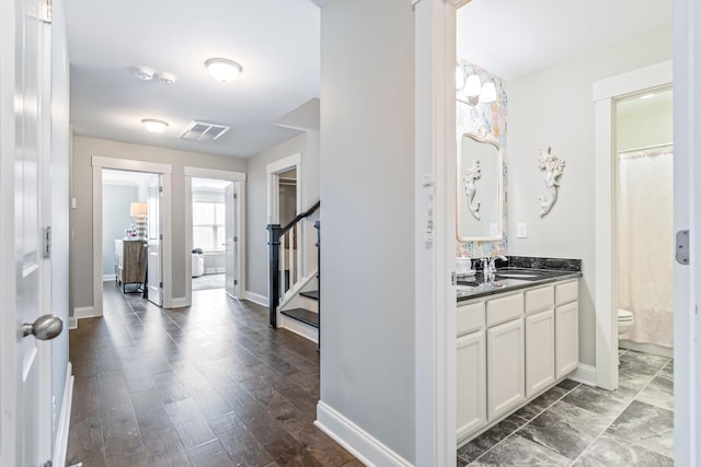 bathroom featuring baseboards, visible vents, toilet, wood finished floors, and vanity