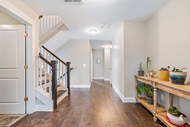 foyer entrance featuring visible vents, dark wood finished floors, stairway, and baseboards