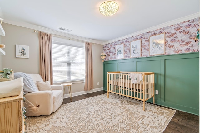 bedroom with ornamental molding, wainscoting, visible vents, and wood finished floors