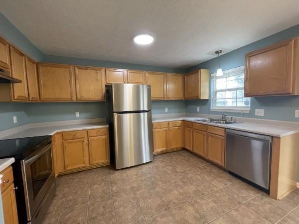 kitchen with appliances with stainless steel finishes, light countertops, and a sink