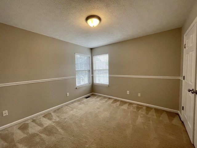 carpeted spare room with a textured ceiling and baseboards