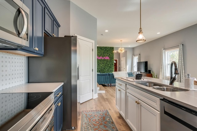 kitchen with blue cabinets, stainless steel appliances, light countertops, light wood-style floors, and a sink