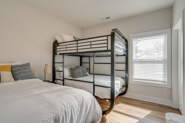 bedroom featuring visible vents, baseboards, and wood finished floors