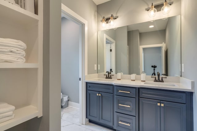 full bathroom with marble finish floor, double vanity, a sink, and baseboards