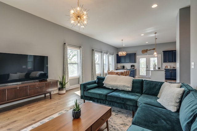 living room featuring an inviting chandelier, light wood-style flooring, baseboards, and recessed lighting