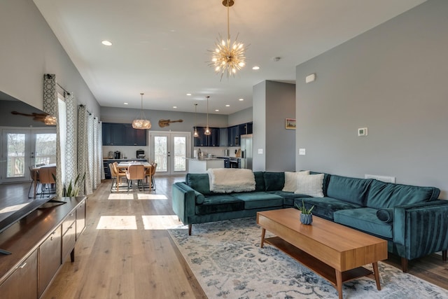 living room featuring light wood finished floors, french doors, recessed lighting, and a notable chandelier