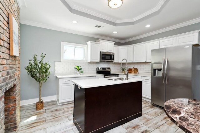 kitchen featuring appliances with stainless steel finishes, a raised ceiling, visible vents, and tasteful backsplash