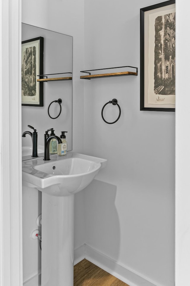 bathroom with a sink, baseboards, and wood finished floors