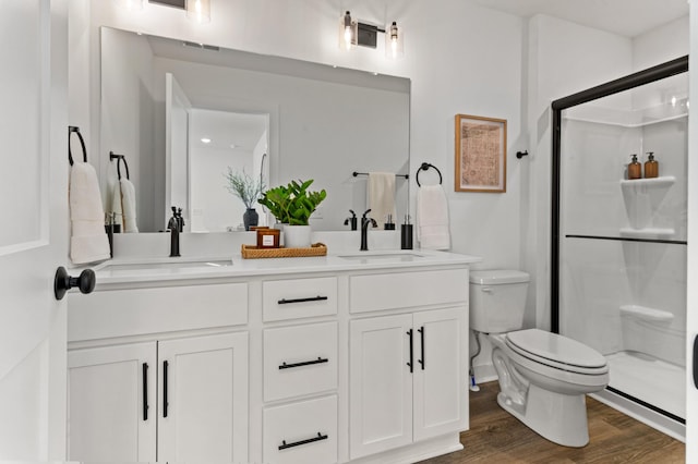 bathroom featuring a sink, a shower stall, toilet, and wood finished floors