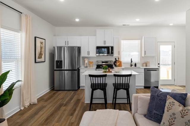 kitchen featuring appliances with stainless steel finishes, open floor plan, light countertops, white cabinetry, and a sink