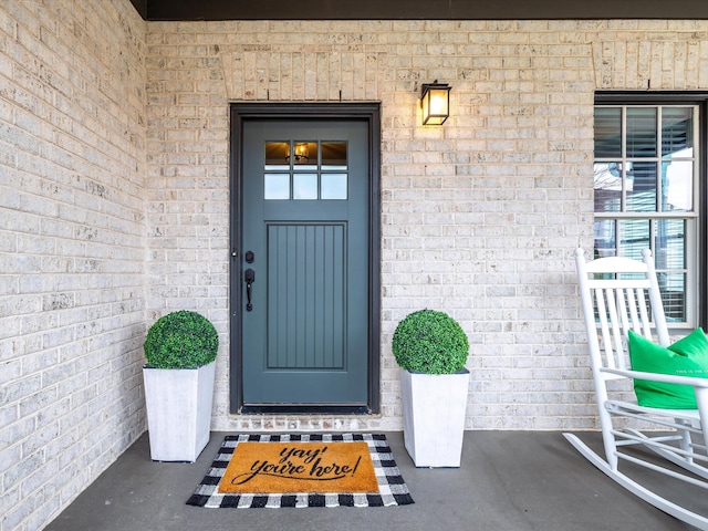 property entrance featuring covered porch and brick siding