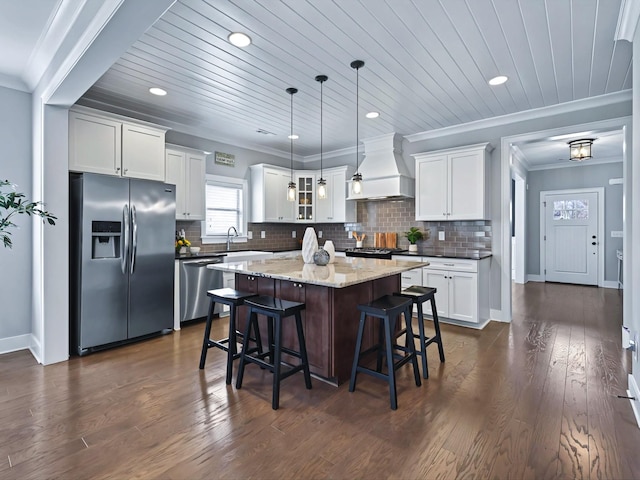 kitchen with premium range hood, appliances with stainless steel finishes, backsplash, and a kitchen island