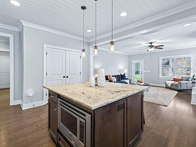 kitchen with dark wood finished floors, crown molding, stainless steel microwave, open floor plan, and dark brown cabinets