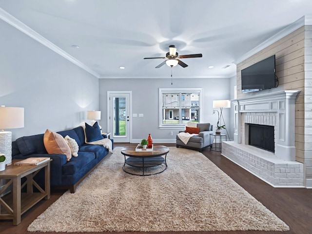 living area with ceiling fan, dark wood-style flooring, a fireplace, and crown molding