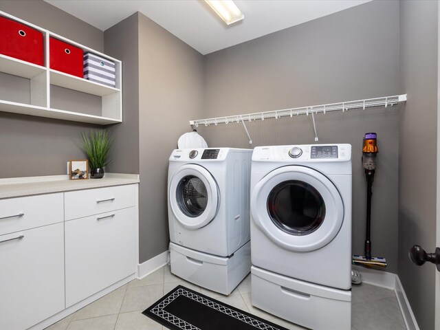 clothes washing area featuring laundry area, washing machine and dryer, baseboards, and light tile patterned flooring