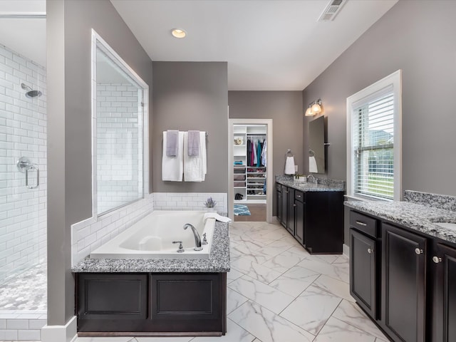 bathroom with marble finish floor, a stall shower, two vanities, and visible vents