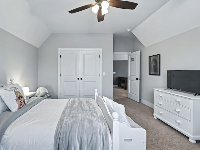 bedroom with lofted ceiling, a closet, light colored carpet, a ceiling fan, and baseboards