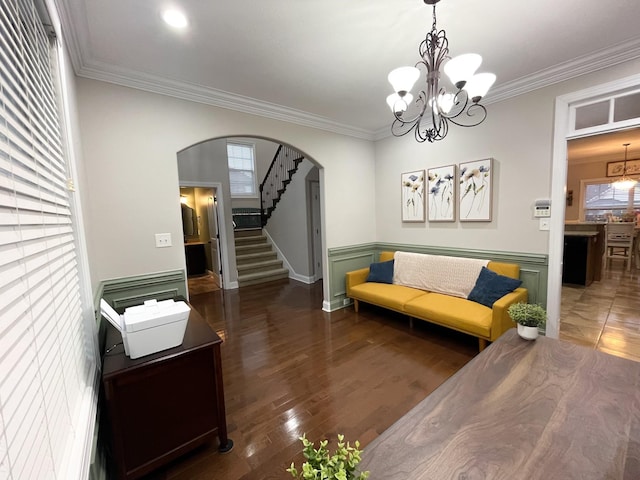 living room featuring arched walkways, stairway, and crown molding