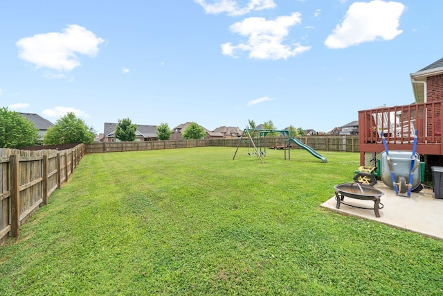 view of yard featuring an outdoor fire pit, a fenced backyard, a playground, and a patio