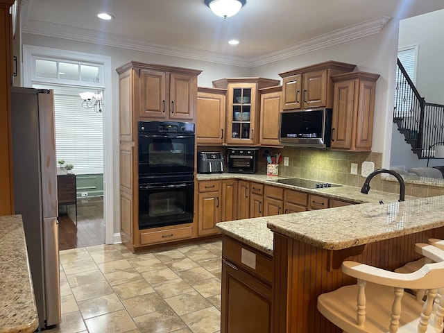 kitchen featuring a breakfast bar area, a peninsula, ornamental molding, black appliances, and tasteful backsplash