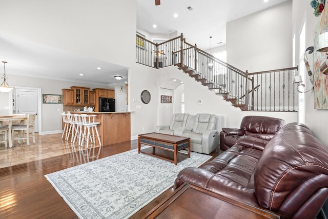 living area featuring baseboards, arched walkways, stairway, ornamental molding, and wood finished floors