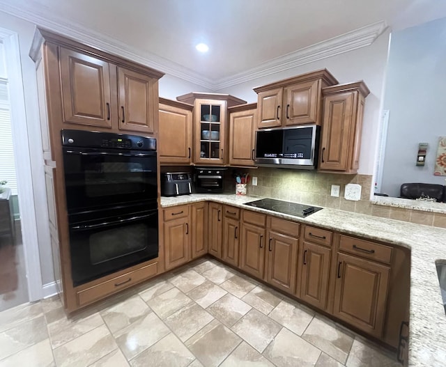 kitchen with black appliances, crown molding, light stone counters, and backsplash