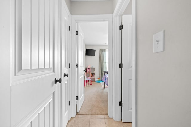 corridor featuring light tile patterned floors and light carpet