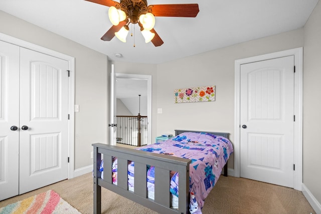 carpeted bedroom with a closet, baseboards, and a ceiling fan