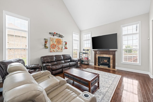 living room with high vaulted ceiling, dark wood-style flooring, a healthy amount of sunlight, and a fireplace