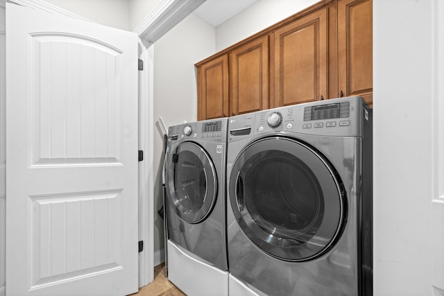 washroom featuring cabinet space and washer and clothes dryer