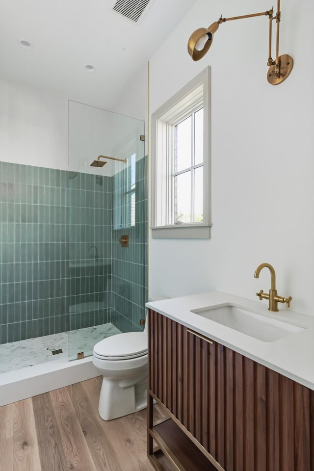 full bathroom featuring a tile shower, visible vents, a sink, and toilet