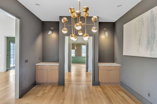 interior space featuring light wood-type flooring, a notable chandelier, and baseboards