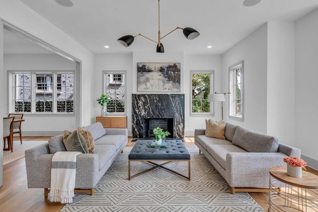 living room featuring a premium fireplace, baseboards, wood finished floors, and recessed lighting