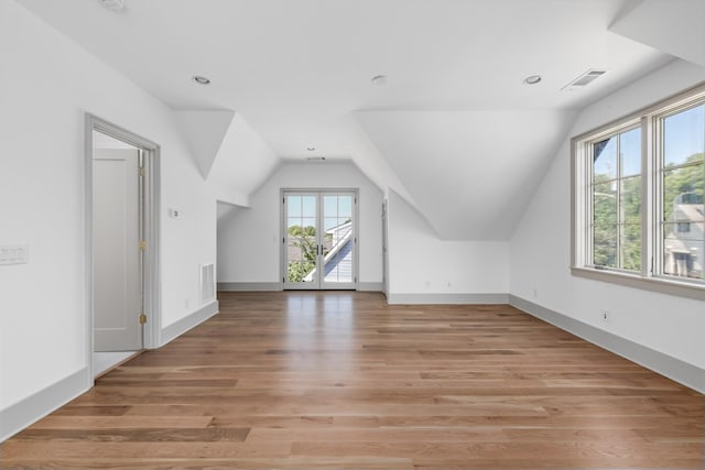 bonus room with light wood-type flooring, baseboards, visible vents, and lofted ceiling