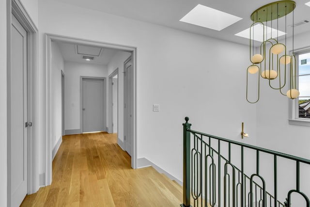 corridor with light wood-style floors, baseboards, visible vents, and an upstairs landing