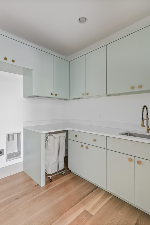 kitchen with light wood finished floors, light countertops, and a sink