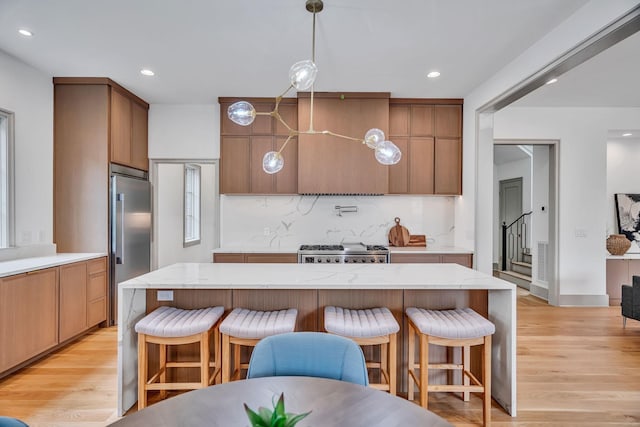 kitchen with tasteful backsplash, stainless steel built in refrigerator, stove, and a breakfast bar area