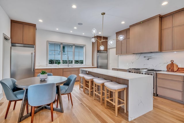 kitchen featuring a center island, high end appliances, recessed lighting, backsplash, and light wood-style flooring