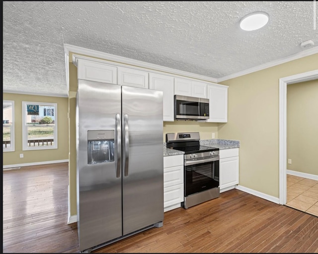 kitchen with dark wood-style floors, crown molding, appliances with stainless steel finishes, white cabinets, and a textured ceiling