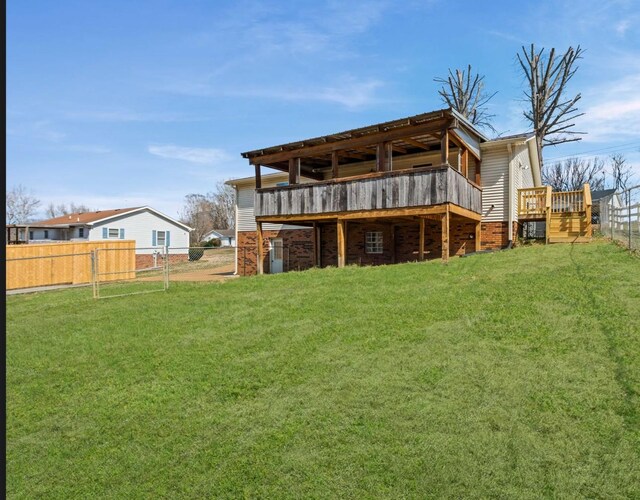 back of house featuring fence, a deck, and a lawn