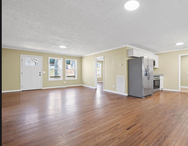 unfurnished living room with visible vents, baseboards, wood-type flooring, ornamental molding, and a textured ceiling