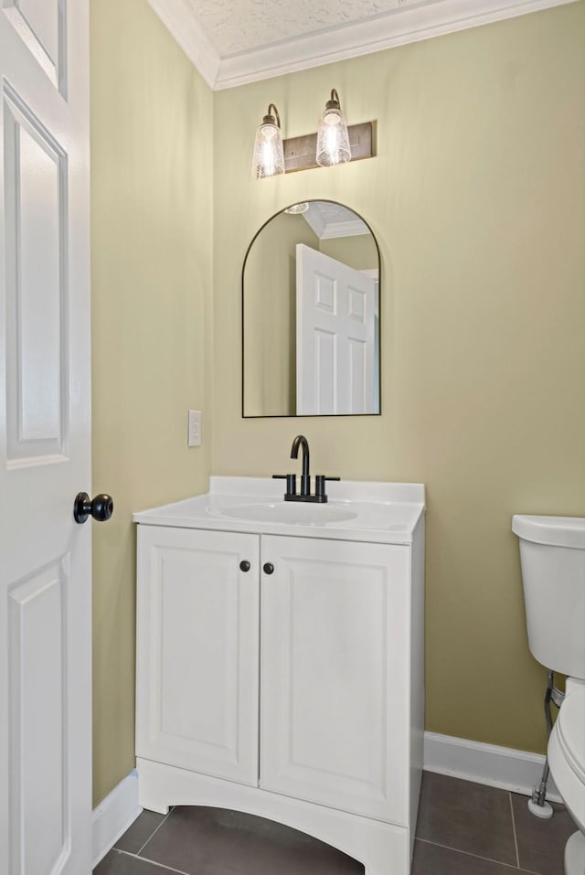 half bath with toilet, vanity, crown molding, and tile patterned floors