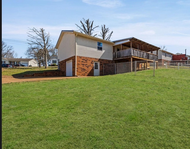 rear view of property featuring an attached garage, fence, a lawn, and brick siding