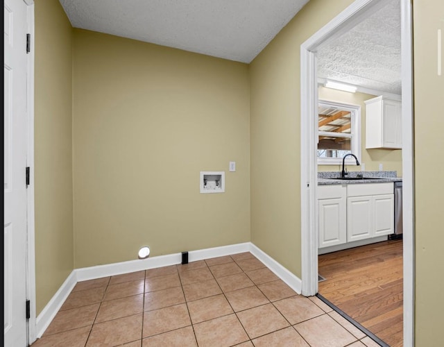 clothes washing area featuring light tile patterned floors, laundry area, washer hookup, a sink, and baseboards