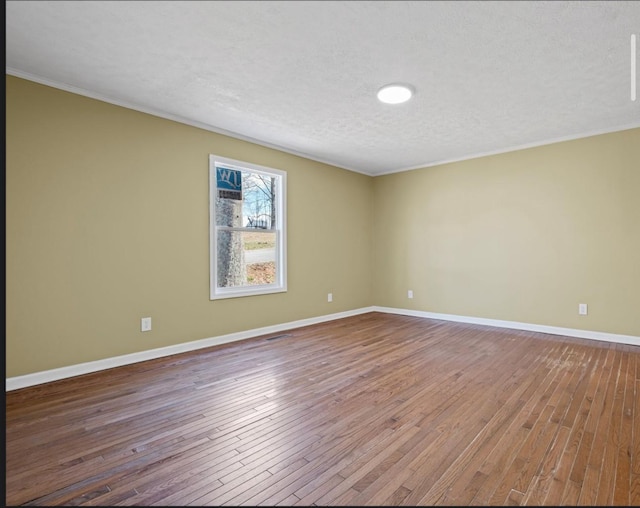 empty room featuring baseboards, crown molding, a textured ceiling, and hardwood / wood-style floors