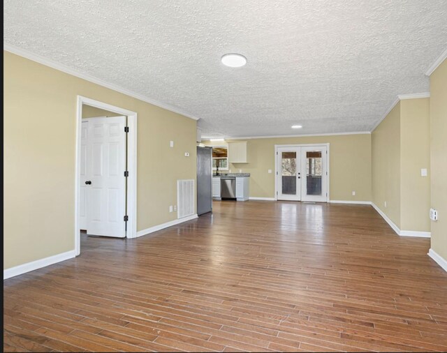 unfurnished living room featuring french doors, visible vents, crown molding, and wood finished floors