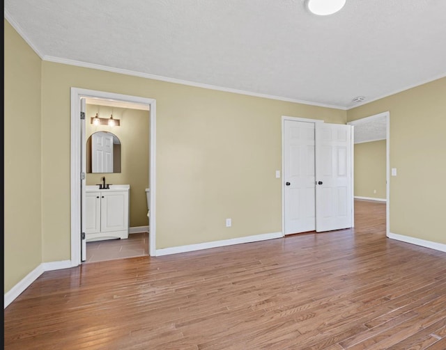 unfurnished bedroom featuring light wood-style floors, baseboards, and crown molding