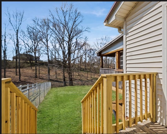 wooden terrace featuring a lawn and fence