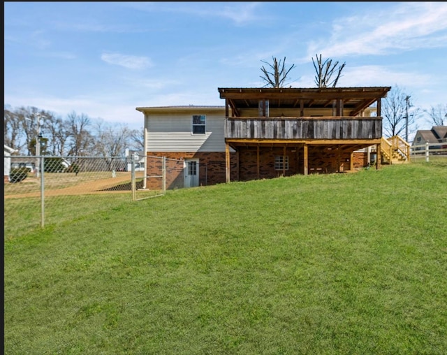 rear view of property featuring a yard, a wooden deck, and fence